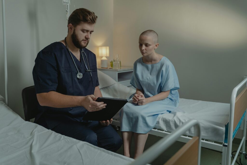 pexels-photo-6010865-6010865 A doctor in a hospital ward consulting a patient with a digital tablet.