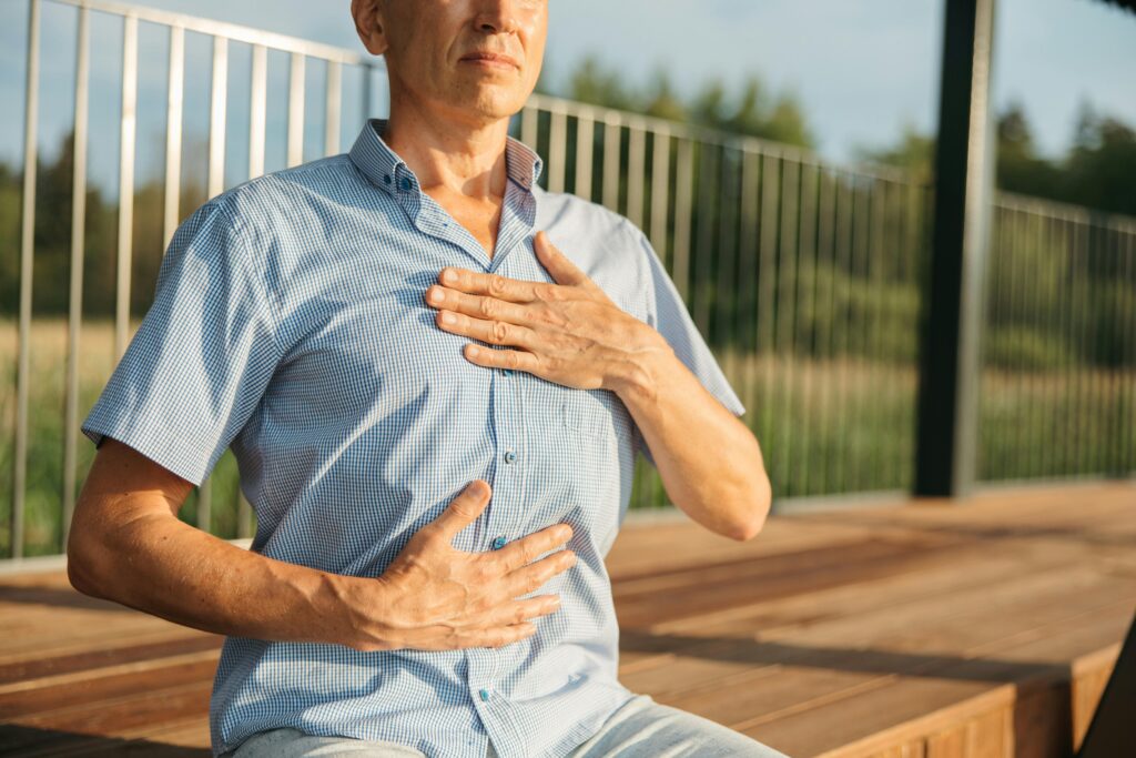 pexels-photo-8795388-8795388 A man practicing relaxation with hands on chest and abdomen outdoors.